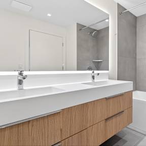 A modern bathroom with a white sink and wooden drawers.