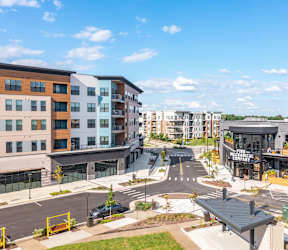 A city street with cars and buildings with a sign at The District at Deerfield Residences Apartments, Mason, OH, 45040