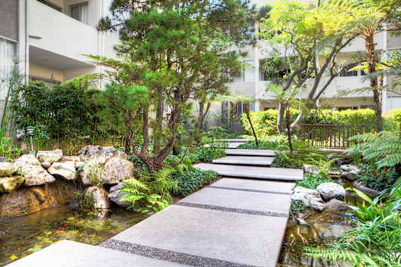 A garden with a stone pathway leading to a pond.