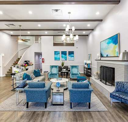 a living room with blue chairs and a fireplace  at The Park at Chesterfield Apartment Homes, Tampa, Florida