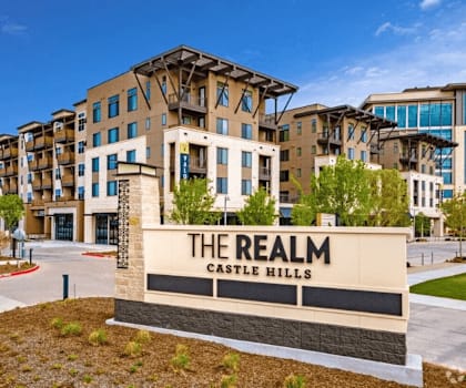 an apartment building with a sign that reads the realm castle hills