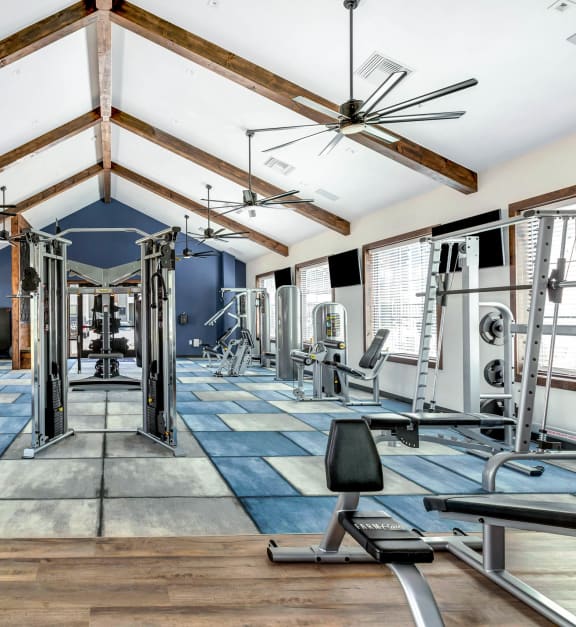 a gym with cardio equipment and weights on the floor and ceiling fans at Farmhaus Apartments, Alabama, 35757