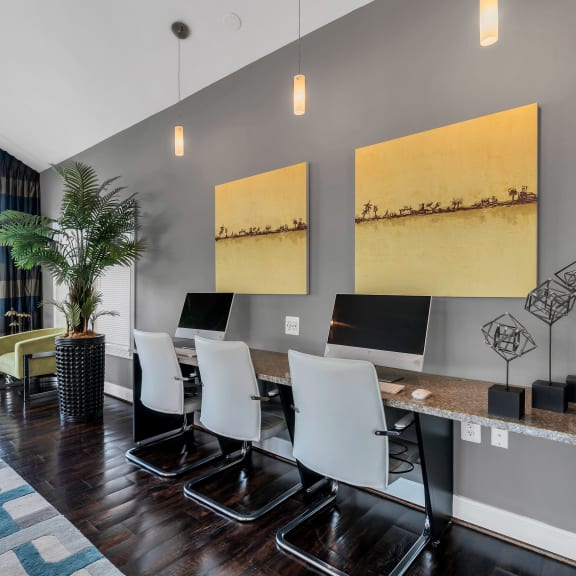 a room with a long desk with four computers on it and two large paintings on the wall at Misty Ridge Apartments, Woodbridge, Virginia