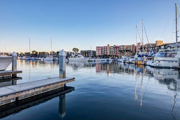 A serene marina with boats docked and buildings in the background.