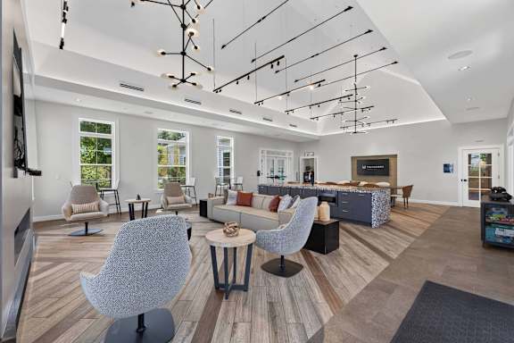 Spacious clubhouse lounge with multiple seating areas, high ceilings, and modern lighting.