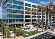 Thumbnail 3 of 12 - A modern building with palm trees in front.