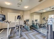 Thumbnail 4 of 4 - A gym with treadmills, exercise bikes, and a television.