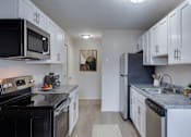 Thumbnail 2 of 5 - A kitchen with black appliances and white cabinets.