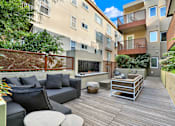 Thumbnail 13 of 41 - A patio with a black couch and a wooden table.