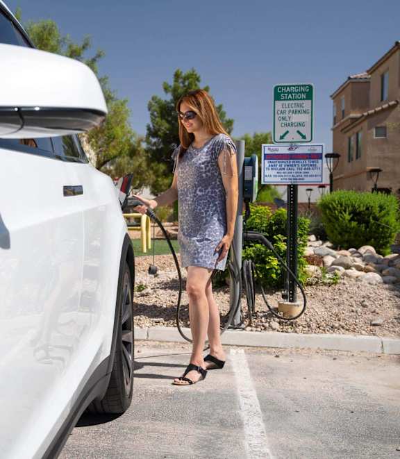 A woman is charging an electric car at a charging station.