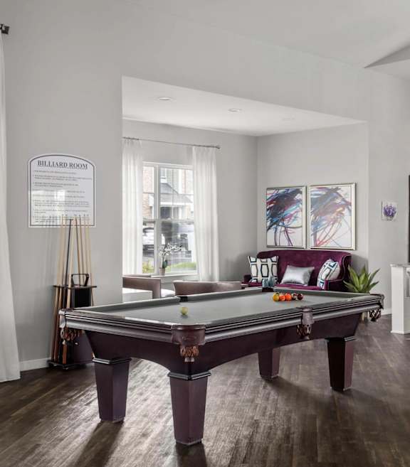 A billiard table is in the middle of a room with a pool table sign on the wall.