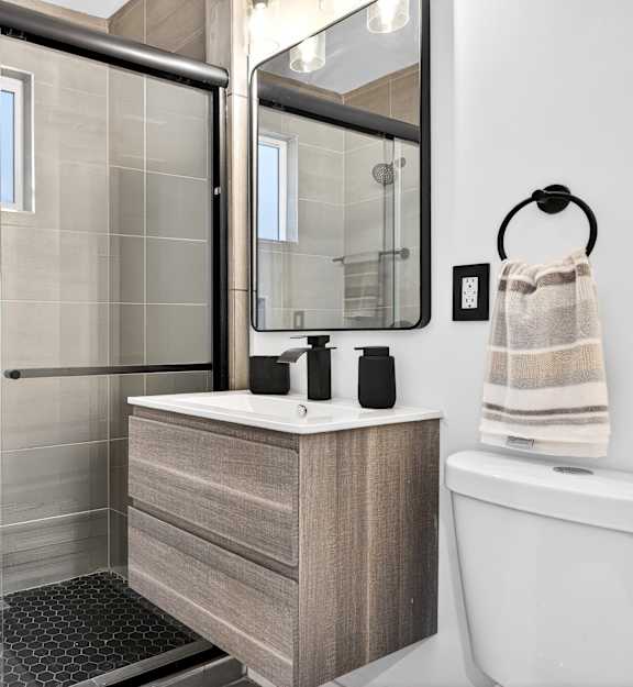 A modern bathroom with a walk-in shower and a large mirror above the vanity.
