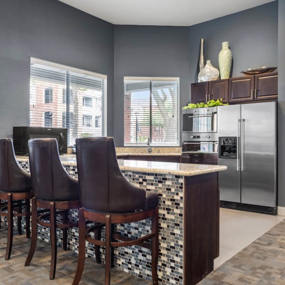 a kitchen with a bar and a stainless steel refrigerator at Veranda at Centerfield in Houston, TX 77070