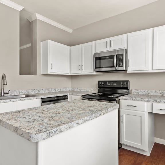 a kitchen with white cabinets and granite counter tops at Villages of Cypress Creek, Houston, Texas