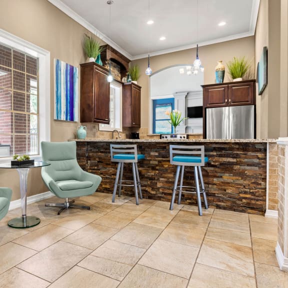 a living room with a kitchen with a bar and chairs