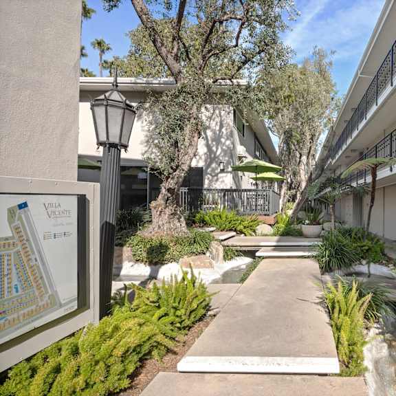 A pathway leads through a landscaped courtyard with a map of the area on the left.