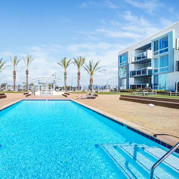 A swimming pool in front of a building with palm trees.