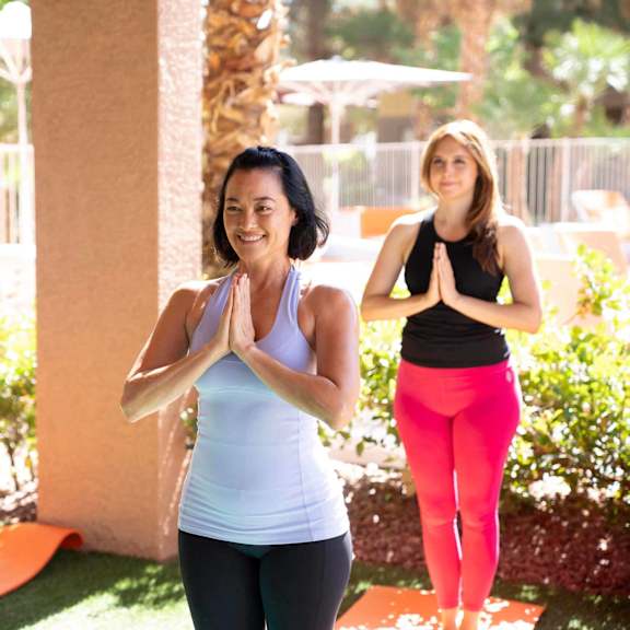 Three people are practicing yoga outdoors.