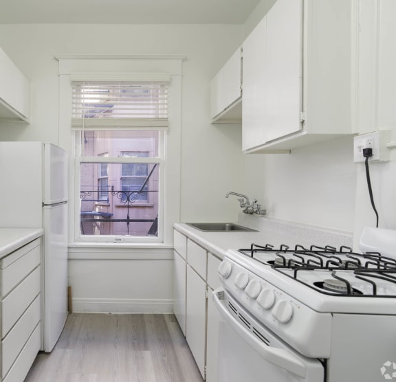 a white kitchen with a stove and a window at Clay & Tiffany, Portland, OR