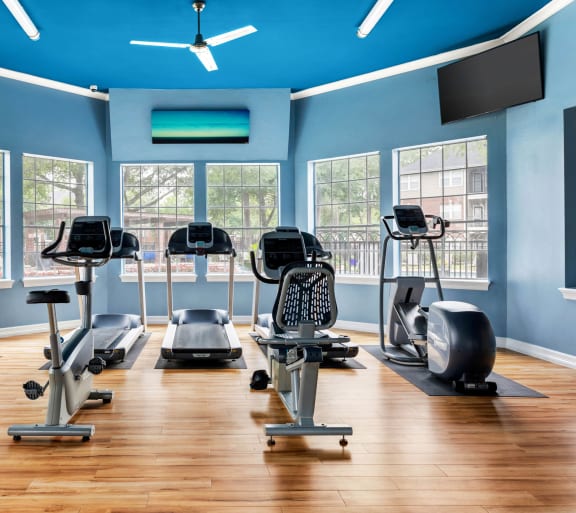 a gym with cardio equipment and windows at Villages of Cypress Creek, Houston, Texas