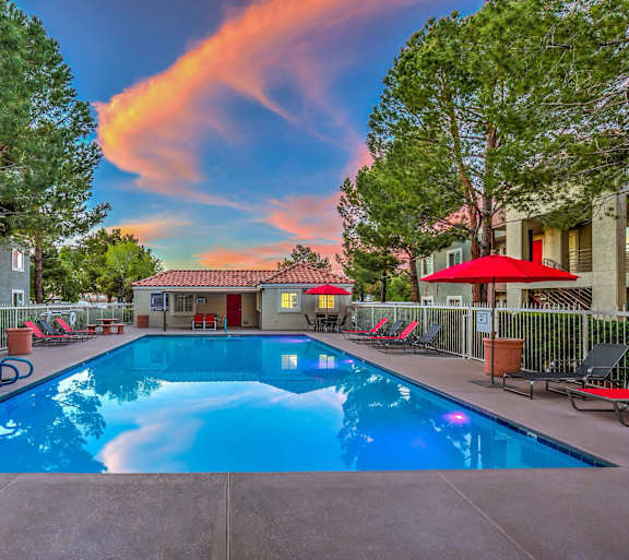 A swimming pool surrounded by lounge chairs and trees.