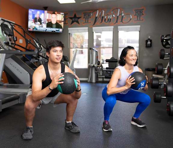 A man and a woman are exercising in a gym.