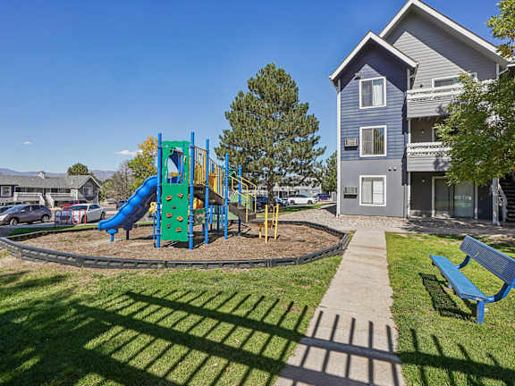 A playground with a blue slide and a green slide in the middle of a grassy area.
