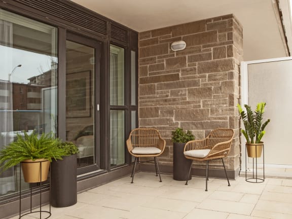 a patio with two chairs and potted plants