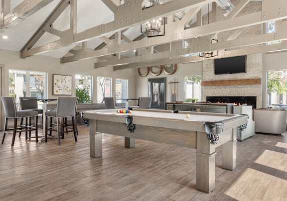 A pool table is in the middle of a room with a fireplace and a TV.