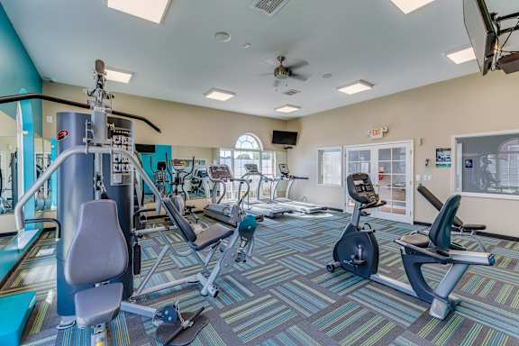 A gym with a variety of equipment including treadmills, weights, and exercise machines.