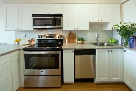 a modern kitchen with stainless steel appliances and white cabinets
