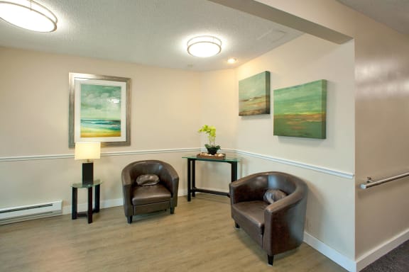 a waiting room with two chairs and paintings on the wall
