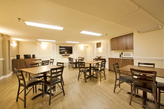 a multipurpose room with tables and chairs and a kitchen