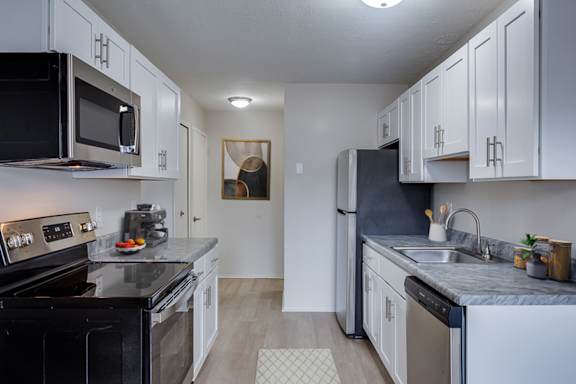 A kitchen with black appliances and white cabinets.