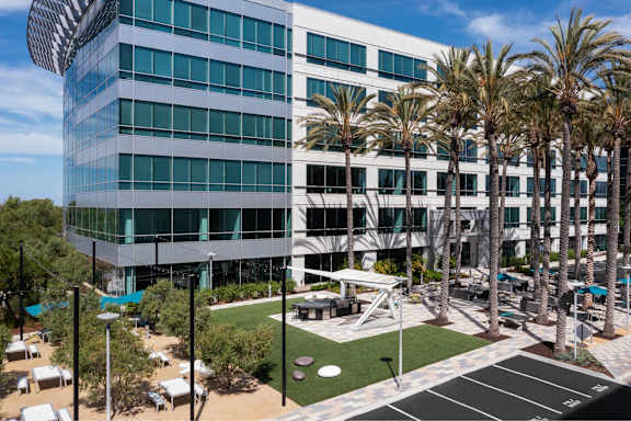 A modern building with palm trees in front.