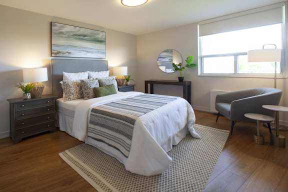 a bedroom with a bed and a chair and a window