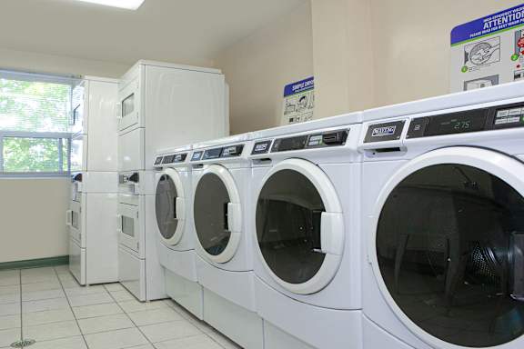 a row of washing machines and dryers in a laundry room