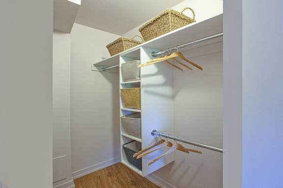 a walk in closet with a white door and shelves with baskets and hangers