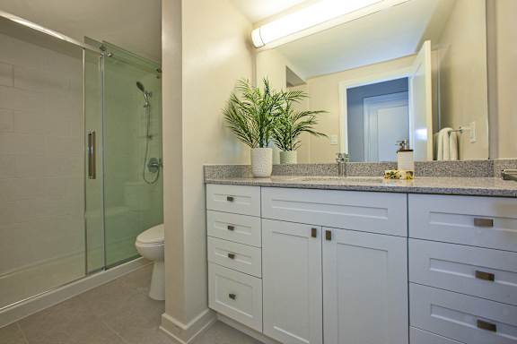 a bathroom with white cabinets and a toilet and a shower