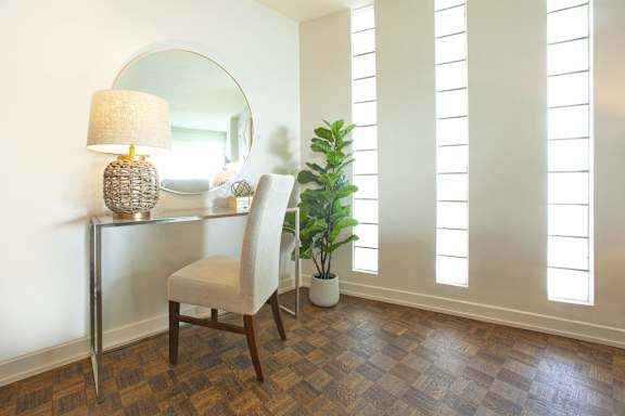 a room with a desk with a mirror and a chair and a plant