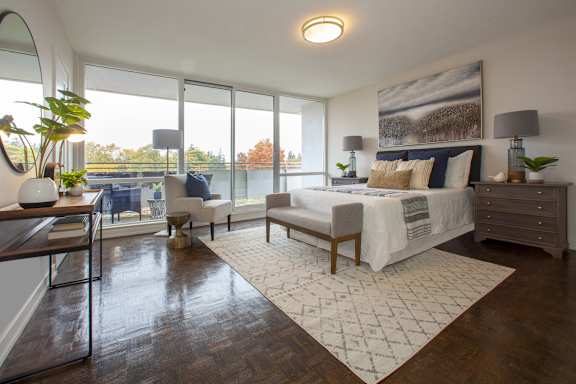 a bedroom with a large window and a bed and a rug