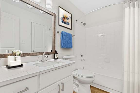 A white bathroom with a blue towel hanging on the towel rack.