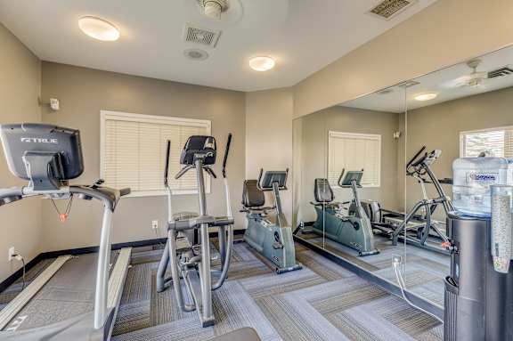 A gym with treadmills, exercise bikes, and a television.