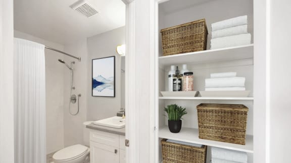 a bathroom with a toilet sink and shelves with towels