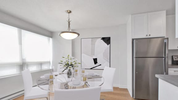 a dining room with a glass table and chairs and a stainless steel refrigerator
