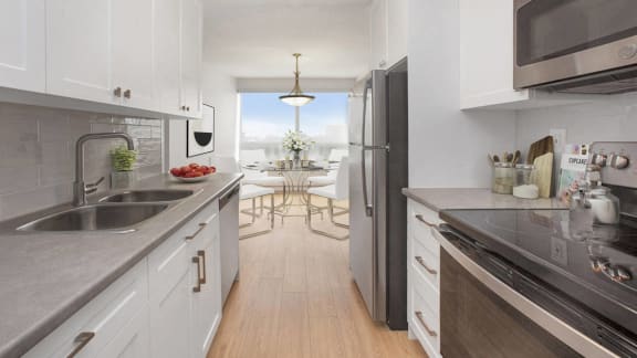 a kitchen with white cabinets and stainless steel appliances and a sliding door to a balcony