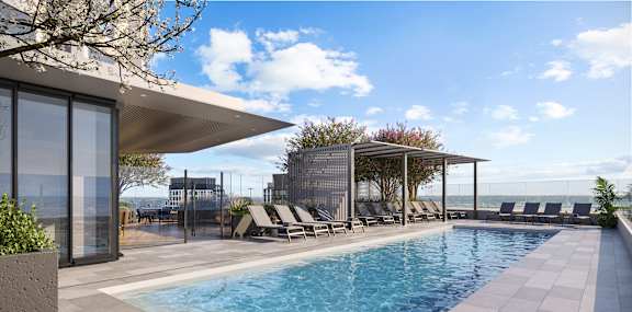 A modern pool area with a clear blue pool and lounge chairs.