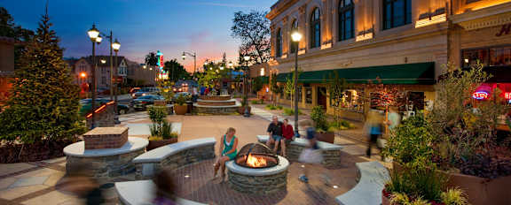 A busy square with a fountain in the middle of it.