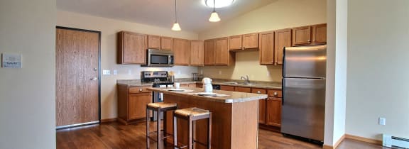 an empty living room with a kitchen in the background