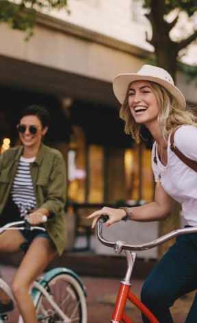 two women riding bikes down a city street at Pearce at Pavilion Luxury Apartments, Riverview, 33578